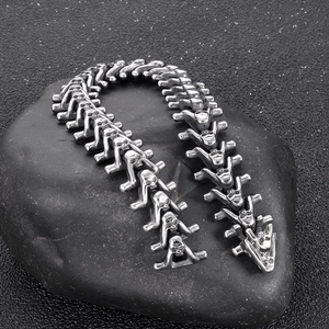 Detail of vintage silver skull spine bracelet on black stone showing gothic metal texture