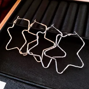 Minimalist large star shaped hoop earrings in gold and silver plating on black tray