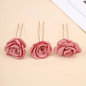 Detailed view of three dusty pink silk rose bridal hair pins with golden U-shaped clips
