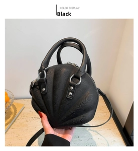 Close-up of black shell-shaped bag featuring embossed floral textures and silver hardware