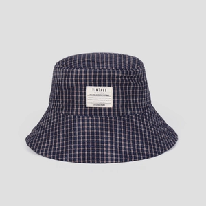 Detail of navy blue plaid bucket hat fabric with a white vintage decorative label