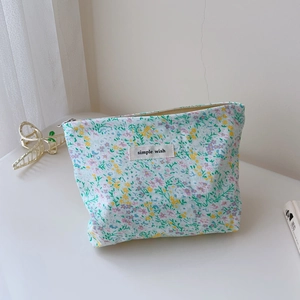 Detail of floral makeup bag with simple wish label and silver zipper on white surface