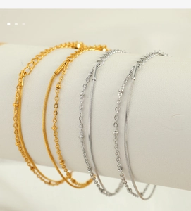 Detailed view of gold and silver snake chains and beaded cross bracelets on a white display
