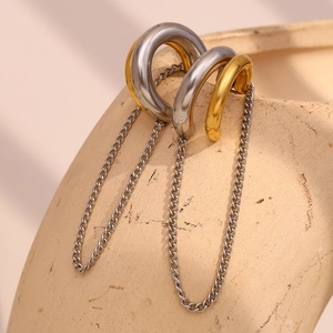Macro view of minimalist dual-tone gold and silver chain earrings on a ceramic rim