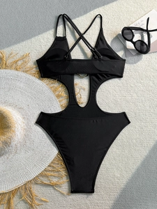 Detail of black cut-out swimsuit featuring a golden heart buckle on textured carpet
