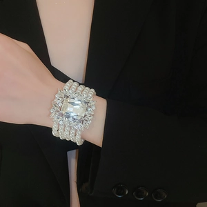Detailed shot of a multi-layer pearl bracelet with a large central crystal on wrist