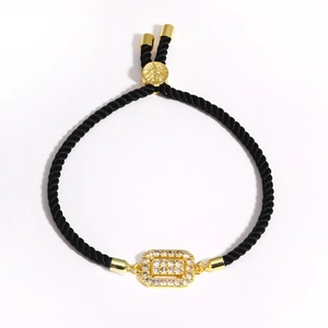 Detail of black woven rope bracelet featuring a gold rectangular zircon-studded charm