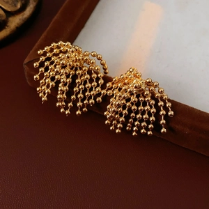 Detailed macro view of gold-plated tassel earrings with beaded chains on velvet