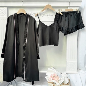 Three-piece black satin pajama set with robe, camisole and ruffled shorts on a hanger