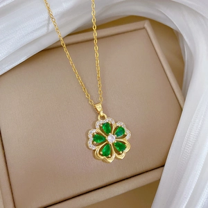 Detail of clover necklace with green water-drop stones and diamonds on beige jewelry box