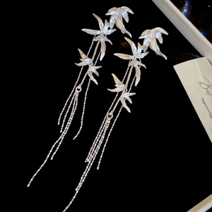 Detail view of silver bamboo leaf earrings with long tassels on black velvet