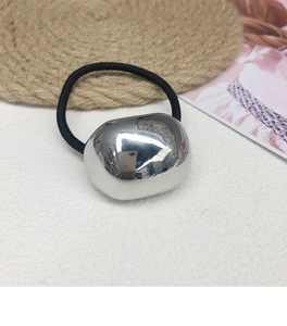 Detail of irregular silver metal pebble accessory on a black high-elastic hair tie