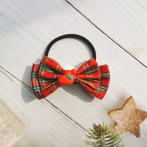 Detail of red and green plaid Christmas bow hair tie with cute Santa sock decoration