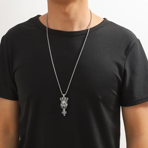 Détail du collier avec pendentif croix tête de lion argenté porté par un modèle homme