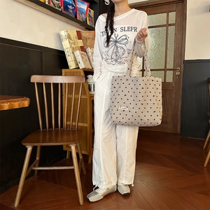 Détail du sac cabas en toile beige avec motifs de pois rouges et petits nœuds