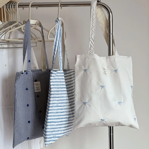 Blue and white striped canvas tote bag collection with elegant bow embroidery detail