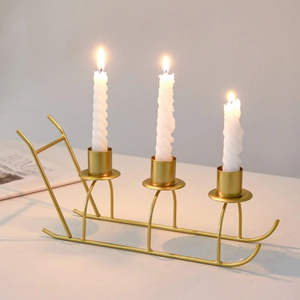 Golden sled metal candle holder with three white spiral candles for festive home decor