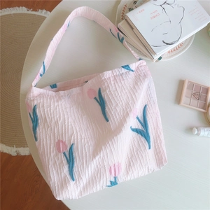 Détail de la broderie de tulipes sur un sac à bandoulière en tissu rose gaufré