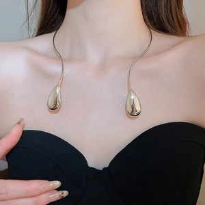 Close-up of silver metallic teardrop collar necklace worn on woman's neck and collarbone