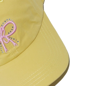 Detail of yellow cotton baseball cap with pink butterfly embroidery and rhinestone accents