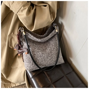 Close-up of grey tweed bucket bag texture with leather puppy charm on a stool