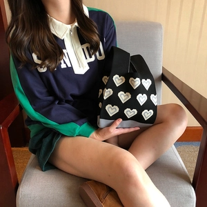 Chic knitted heart tote bag in black and blue shown in a model handheld lifestyle setting