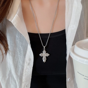 Close-up of a silver cross pendant necklace with sparkling rhinestones worn by a model