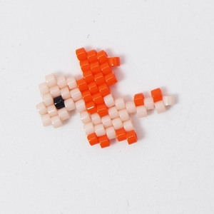 Handmade orange and pink Miyuki bead dinosaur charm for jewelry making on white background
