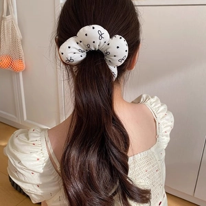 Polka dot fabric scrunchie with bow pattern worn on a bun for a sweet hairstyle