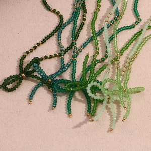 Detailed view of layered green faceted crystal necklaces with gold bead accents and bows
