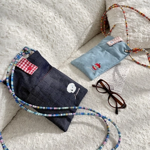 Detail of embroidered denim bags with checkered flaps and colorful beaded straps