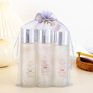 Gray mesh gift bag set with SK-II skincare bottles featuring a ribbon bow and pearls