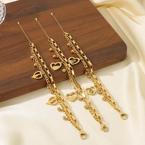 Detailed view of layered gold heart bracelets with charms on silk and wood