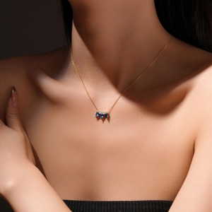 Elegant gold S925 sterling silver crown necklace with teardrop blue gems on a model