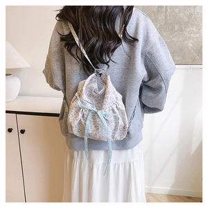 Lifestyle view of a floral drawstring backpack with blue patterns on a female model