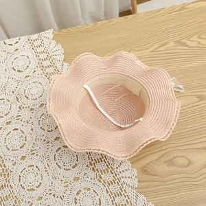 Detailed interior of a pink straw hat with wave lace brim and adjustable wind rope