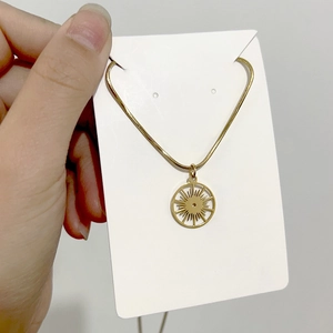 Detail of bohemian sunburst pendant necklace with a gold snake chain on display