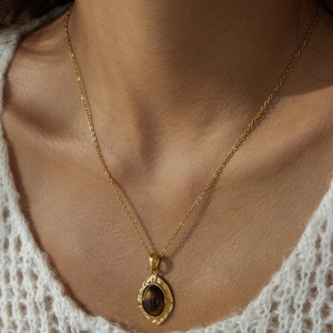 Dettaglio della collana con occhio di tigre in acciaio dorato indossata da una modella