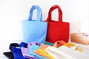 Colorful canvas lunch bags in various vibrant hues arranged with a decorative basket