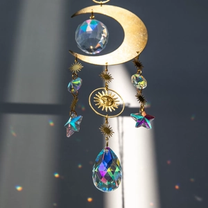 Detail showing brass moon and star suncatcher with crystal prisms reflecting rainbow light