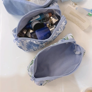 Close-up of blue floral and corduroy pouches showing large storage capacity for cosmetics