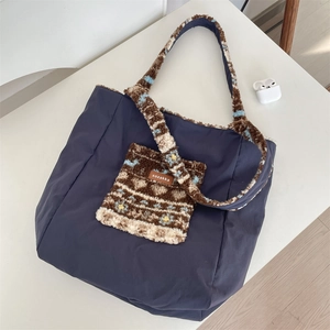Close-up of a navy canvas tote bag featuring ethnic plush strap and front pocket detail