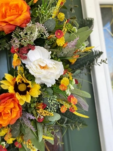 Detail view of colorful eucalyptus wreath with orange roses and yellow sunflowers