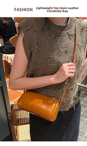 Detailed view of brown leather cylinder crossbody bag worn on model, showing soft texture and strap.