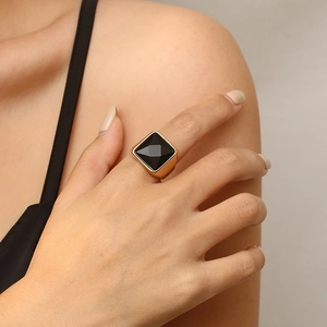 Macro detail of a unisex gold ring featuring a large black square-cut gemstone inlay
