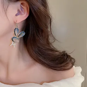Detail of silver needle rabbit earrings with blue stones and zircon butterfly bow accents