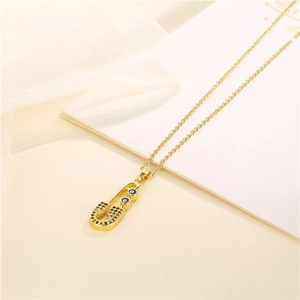 Gold safety pin necklace with colorful zircon and evil eye pendant on beige background