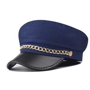 Detailed view of navy blue newsboy hat with black leather brim and gold chain accent