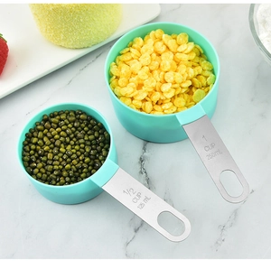 Detail of mint green measuring cups with stainless steel handles on marble surface