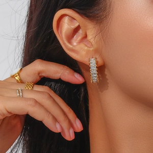 Gros plan de boucles d'oreilles C dorées avec zircons et bagues assorties en or